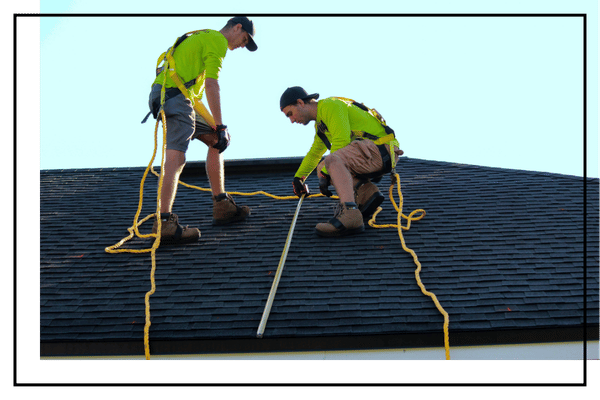 two roofers safely inspecting roof